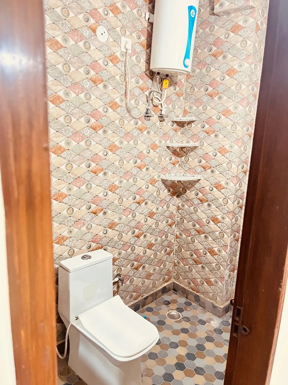 A tiled bathroom with a toilet and wall-mounted water heater.