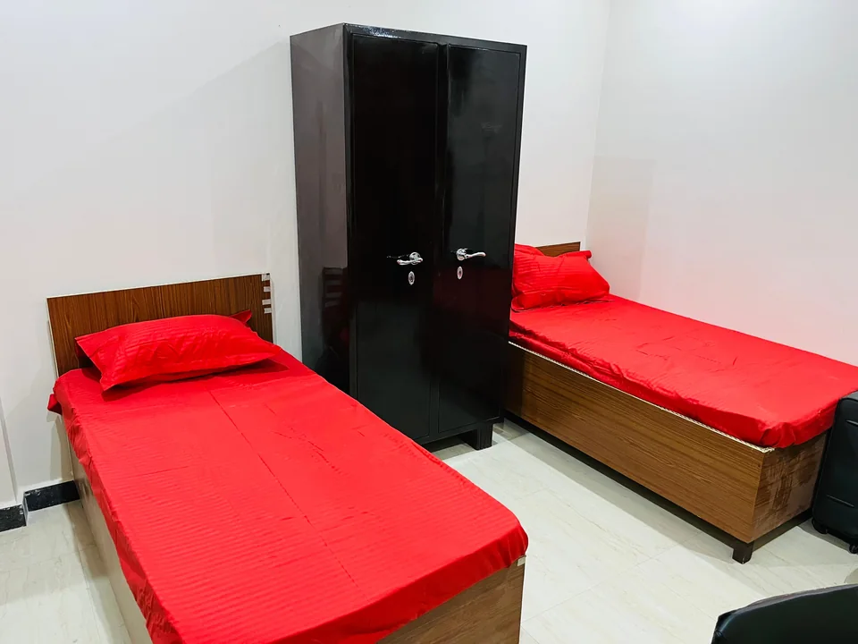 Two single beds with red covers and dark wardrobes.
