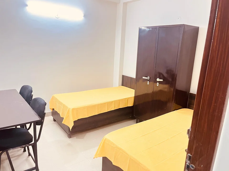 Two beds, a wardrobe and a ceiling fan in a Kings Hostel room.